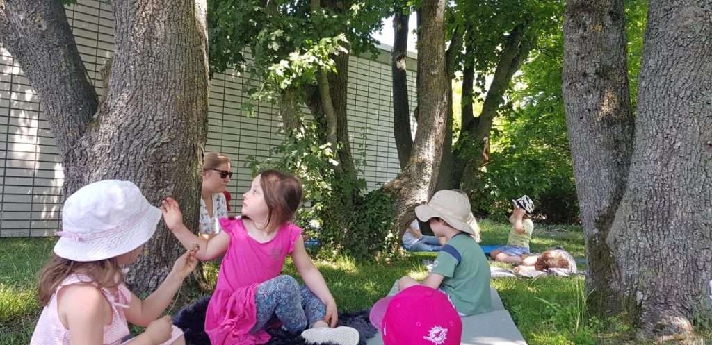 Kinder sitzen im Schatten der Bäume