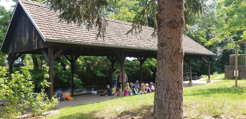 Kinder sitzen zusammen an einem alten Waschplatz und essen zu Mittag