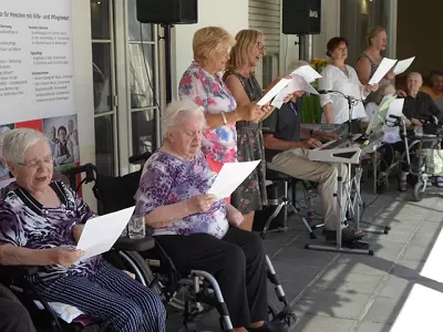 Gruppe von Seniorinnen singen gemeinsam und werden von Keyboard belgeitet