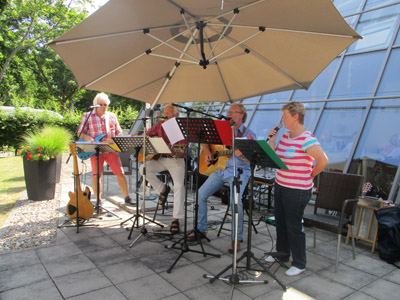 Ein Musikband tritt unter einem Sonnenschirm auf.