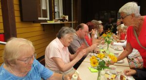 Bewohnerinnen sitzen gemeinsam am Tisch und Essen Kuchen