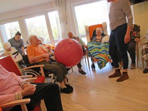 Senioren sitzen im Kreis und spielen mit einem Ball