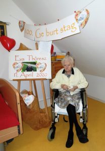 Eine Seniorin sitzt im Rollstuhl und feiert ihren 100. Geburtstag