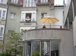 Senior*innen sitzen auf den Balkonen.