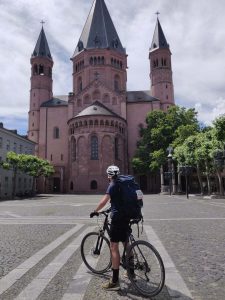 Ein Mann sitzt auf einem Fahrrad und steht vor dem Mainzer Dom.