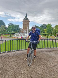 Ein Mann sitzt auf seinem Fahrrad und steht in einem grünen Park.