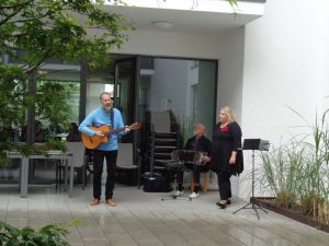 Das Trio Nostalgia steht im Innenhof des Seniorenzentrums Knielingen und macht Musik. 