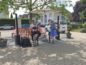 Eine Sängerin und ein Gitarrist geben ein Open Air Konzert im Hof eines Seniorenzentrums.