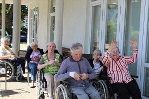 Senior*innen sitzen im Freien und lachen.