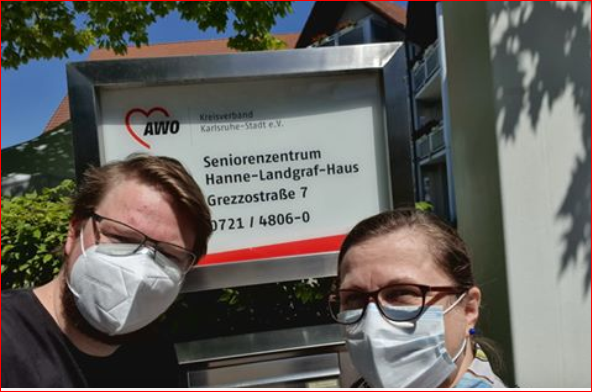 Zwei Menschen mit Mundschutz stehen vor einem Schild auf dem steht Seniorenzentrumm Hanne-Landgraf-Haus