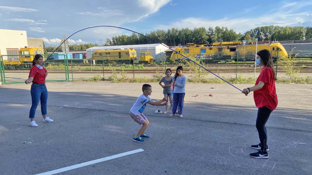 Zwei Kinder schwingen ein Seil und ein drittes Kind hüpft darüber.