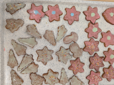 Weihnachtsplätzchen in Stern- und Engelformen liegen auf einem Tablett. Sie sind mit Zuckerguss und bunten Streuseln verziert.