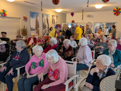 Senioren im Publikum verfolgen sichtlich erfreut eine Tanzdarbietung im festlich geschmückten Speisesaal des AWO Seniorenzentrums.