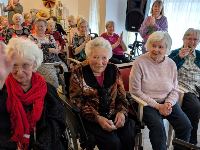 Eine glückliche Bewohnerin mit rotem Schal klatscht im Takt der Musik während der Prunksitzung.