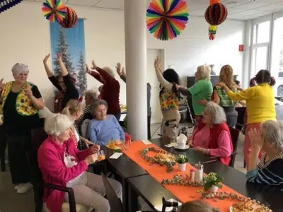 Fröhliche Polonaisegruppe zieht bei der Rosenmontagsparty an dekorierten Tischen vorbei, während Gäste am Rand mitklatschen.