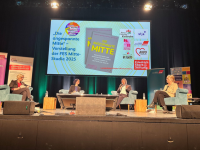 Vier Personen sitzen auf einer Bühne in Sesseln und diskutieren. Im Hintergrund wird die Titelfolie der FES-Mitte-Studie 2025 auf einer großen Leinwand gezeigt.