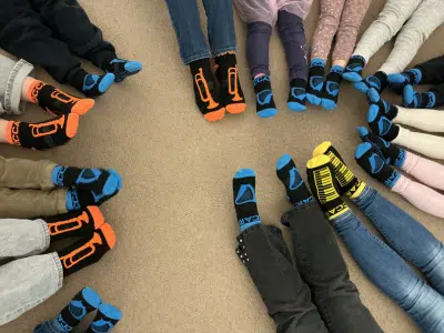 Vorschulkinder sitzen im Kreis und tragen Stoppersocken im Mitmachmuseum, vorbereitet auf Bewegungs- und Klangangebote.