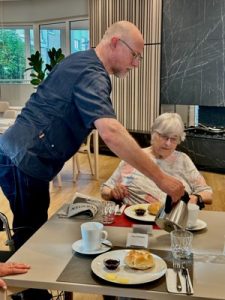 Markus Barton, Geschäftsführer der AWO Karlsruhe, schenkt einer Bewohnerin Kaffee beim Frühstück in einer modernen Senioreneinrichtung ein.