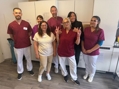 Pflege-Team der AWO Karlsruhe posiert gemeinsam in Arbeitskleidung für ein Gruppenfoto.