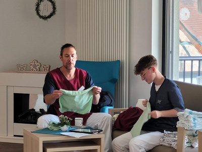 Martin Höfer, Sachgebietsleitung faltet gemeinsam mit einer Hauswirtschaftskraft, Wäsche.