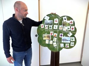 Ein Mitarbeiter präsentiert einen Lernbaum mit Karten zu Jahreszeiten, Pflanzen und Tieren im Rahmen des Klimaspürnasen-Projekts in der Kita Pamina.