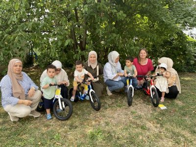 Mehrere Familien mit ihren Kleinkindern stehen im Freien mit neuen Laufrädern, die im Rahmen einer Spendenaktion von Lucky Bike übergeben wurden.