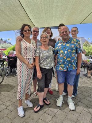 Gruppenfoto des Teams des Seniorenzentrums Knielingen beim Erdbeerfest auf der Terrasse; sieben Mitarbeitende stehen lächelnd unter einem Sonnensegel.