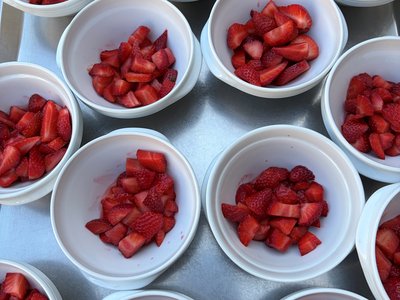 Zahlreiche weiße Schälchen mit frisch geschnittenen Erdbeeren auf einem Tablettwagen, vorbereitet für das Sportfest im AWO Anna Leimbach Haus Karlsruhe.