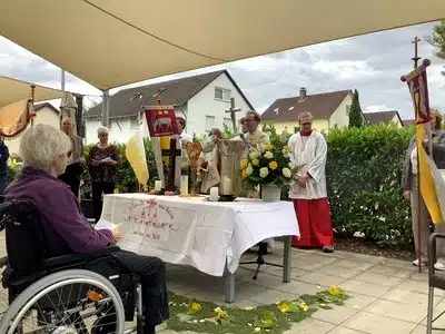 Geschmückter Altar mit Blumen, Fahnen und geistlichen Begleitenden bei der Fronleichnamsprozession.