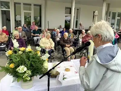 Eine Frau spricht während der Fronleichnamsfeier auf der Terrasse zu den Bewohner*innen.