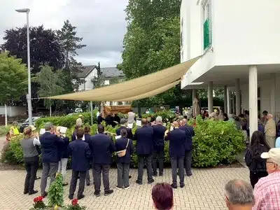 Musiker*innen und Gäste stehen vor dem Seniorenzentrum während der Fronleichnamsprozession.