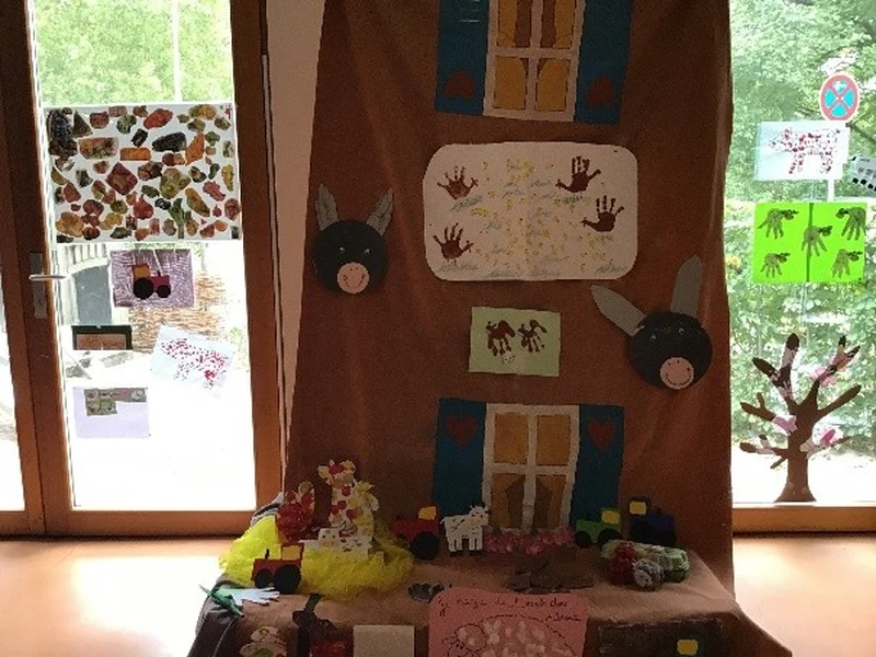 Ausstellung beim Sommerfest mit einer großen gestalteten Bauernhofkulisse, Tierfiguren und Kinderarbeiten: