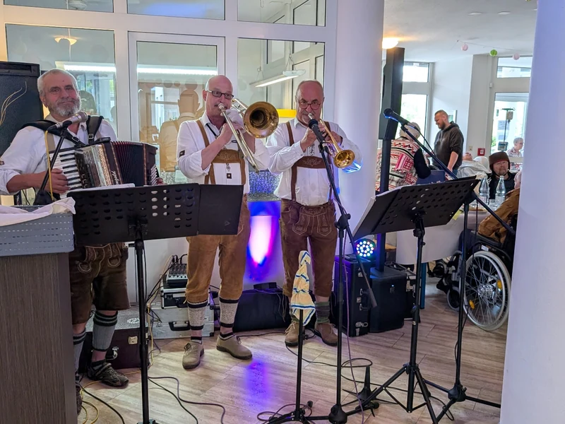 Drei Musiker spielen Akkordeon, Posaune und Trompete im Saal des Hanne-Landgraf-Hauses.