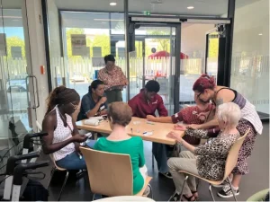 Mehrere Besucher*innen und Mitarbeitende sitzen während der Blutdruckaktion an einem Tisch.