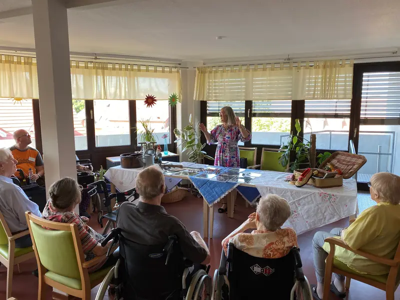 Bewohner*innen des Hauses am Blumentor sitzen mit zwei Kulturvermittlerinnen um einen Tisch.