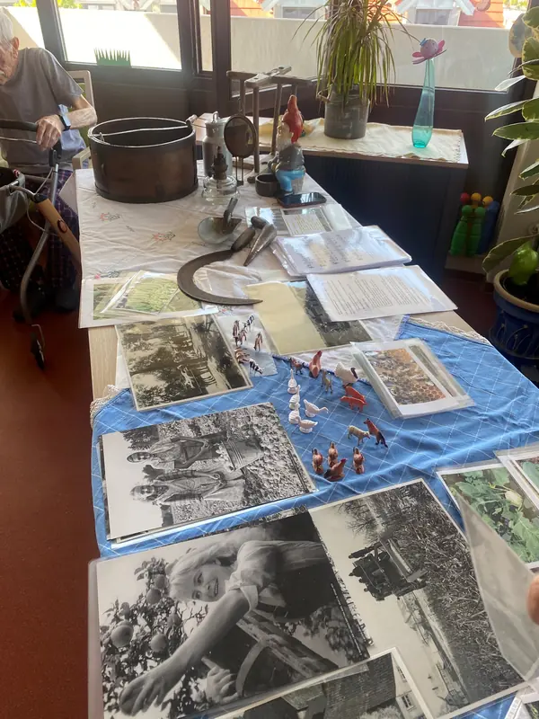 Historische Fotografien und Alltagsgegenstände sind auf einem großen Tisch ausgelegt