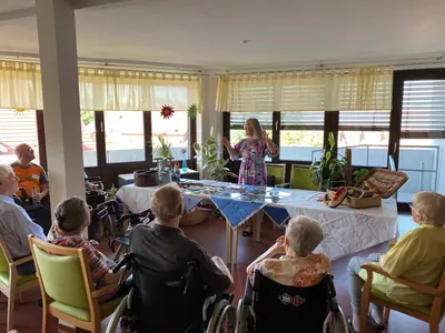 Bewohner*innen des Hauses am Blumentor sitzen mit zwei Kulturvermittlerinnen um einen Tisch.