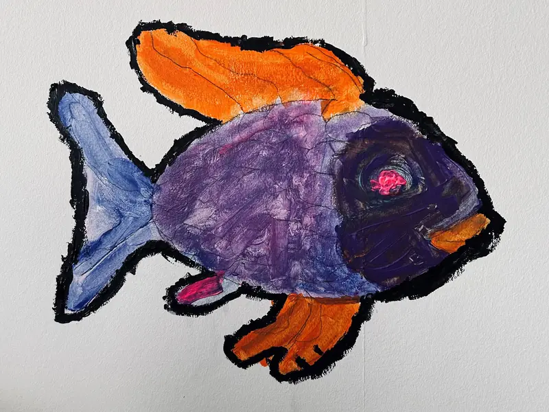 Ein großer, farbig gestalteter Fisch ist an einer weißen Wand angebracht.