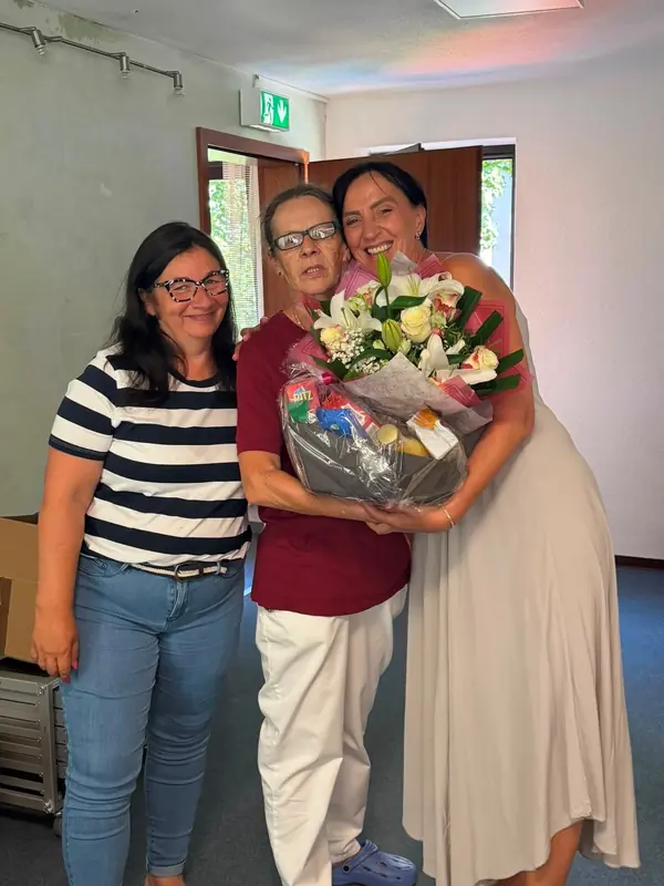 Michaela Hellinger, Anke Agsten und Mirjana Braitsch stehen gemeinsam mit einem Blumenstrauß im Flur.