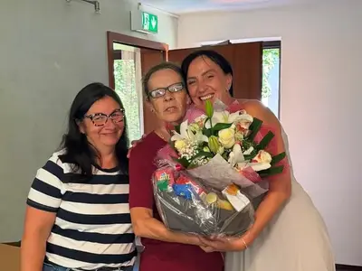 Michaela Hellinger, Anke Agsten und Mirjana Braitsch stehen gemeinsam mit einem Blumenstrauß im Flur.
