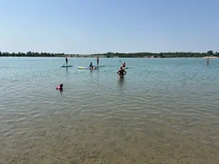 Jugendliche paddeln auf mehreren Stand-up-Paddleboards über den Epplesee.