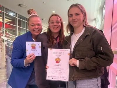 Drei Frauen präsentieren eine Urkunde und eine Plakette mit dem Gütesiegel Buchkita.