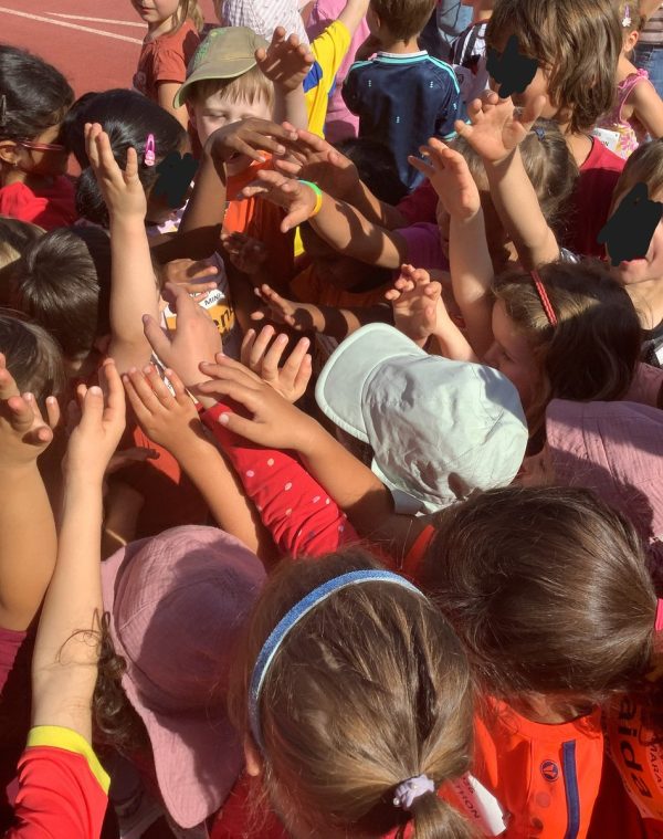 Kinder der Kita Pamina legen vor dem Bambini-Marathon ihre Hände gemeinsam in die Mitte.